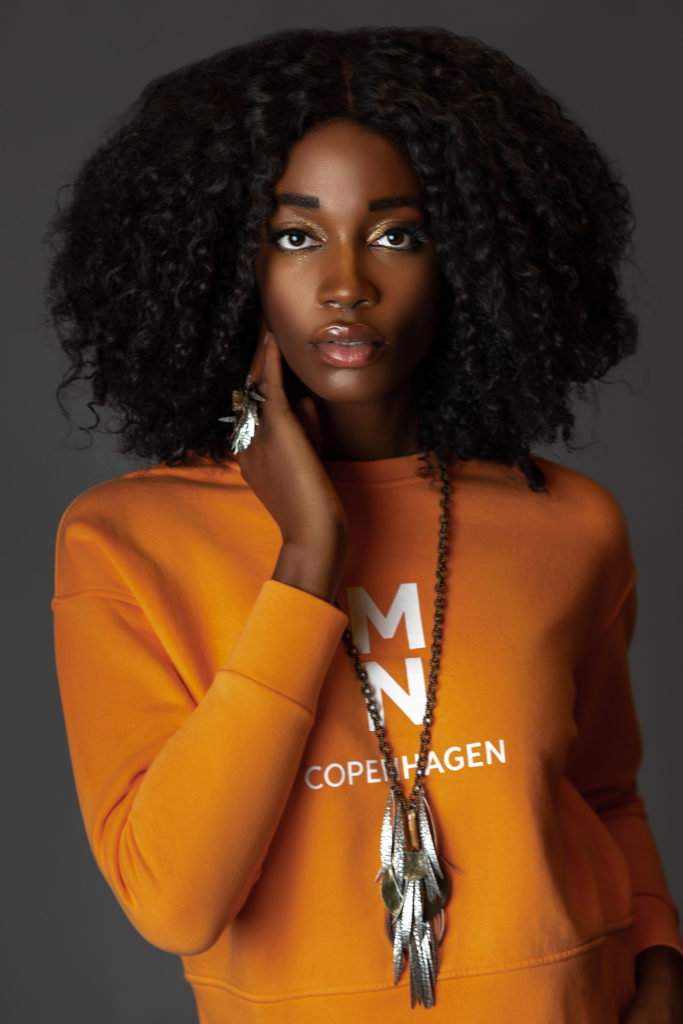 Black girl wearing an orange sweatshirt for Spring 2021 Fashion Trends